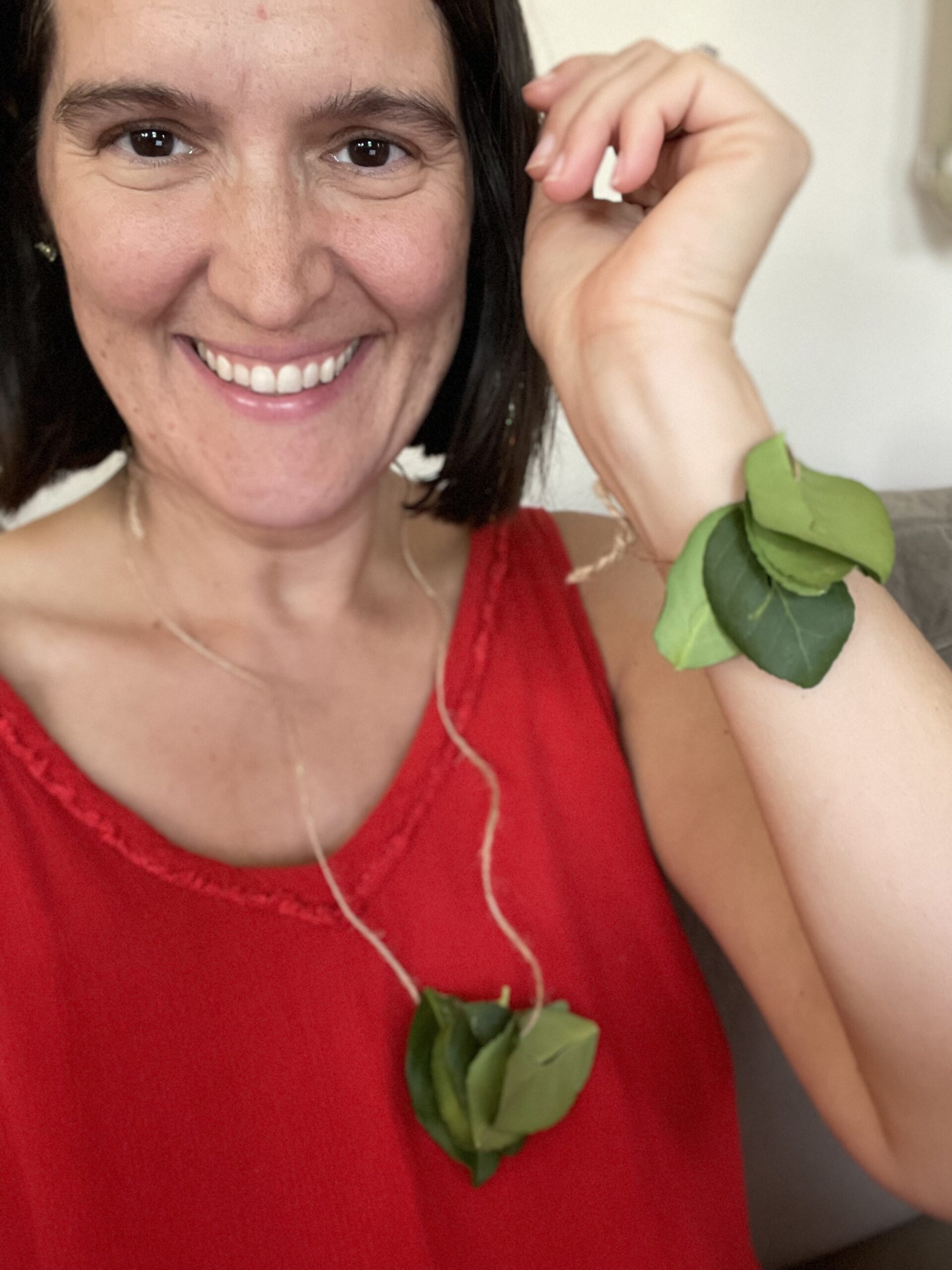 PIcture of Rebecca smiling at the camera in a red dress and leaf necklace and bracelet